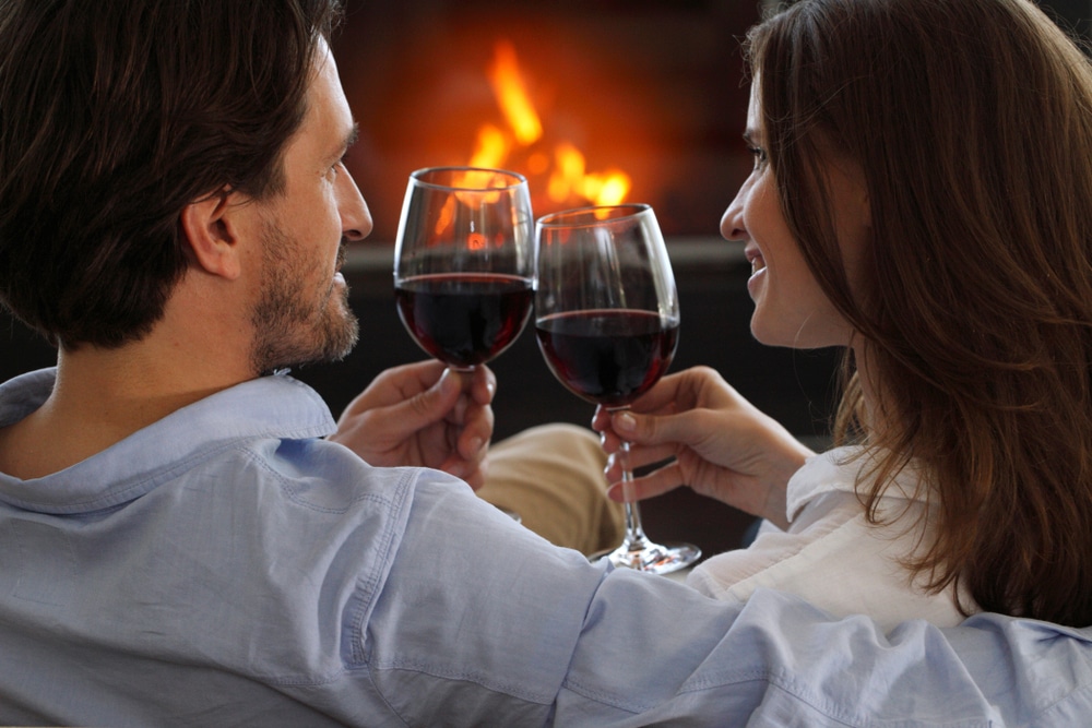 A couple drinking wine by the fire in our luxury cabin in Wisconsin, after enjoying a day of all the best things to do in Wausau in the winter