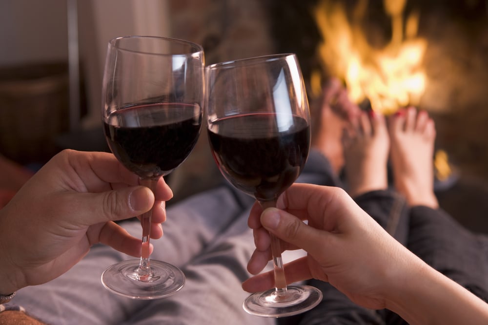 Couple drinking wine by the fire at one of the most romantic cabins in Wisconsin