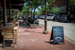 Downtown Wausau sidewalk and shop with a sandwich board. Some of the best things to do in Wausau, WI are as simple as strolling downtown.
